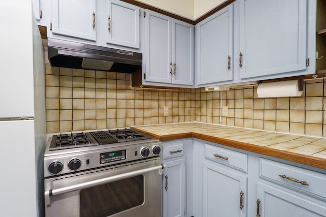 4384 Dexter Pinckney Rd, Dexter, MI 48130 - kitchen with stainless steel gas range oven, freestanding refrigerator, under cabinet range hood, decorative backsplash, and tile counters