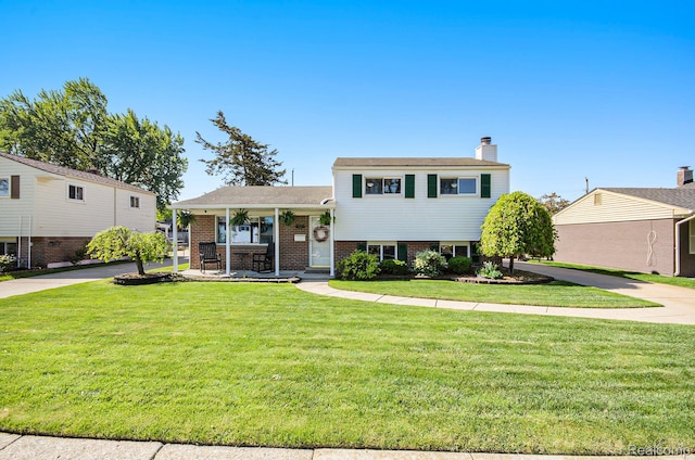 2426 Camel Dr, Sterling Heights, MI 48310 - tri-level home with a front yard, a chimney, a porch, and brick siding