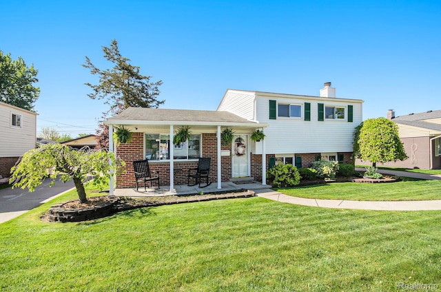 2426 Camel Dr, Sterling Heights, MI 48310 - split level home featuring brick siding, a chimney, covered porch, and a front lawn