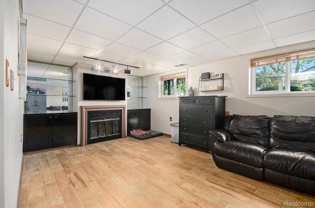 2426 Camel Dr, Sterling Heights, MI 48310 - living room featuring wood finished floors, a drop ceiling, rail lighting, a glass covered fireplace, and healthy amount of natural light