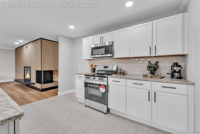 22929 Wrexford Dr, Southfield, MI 48033 - kitchen featuring stainless steel appliances, light wood-style flooring, decorative backsplash, white cabinets, and recessed lighting
