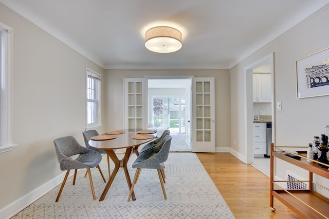 dining room with french doors, light wood-style floors, baseboards, and crown molding