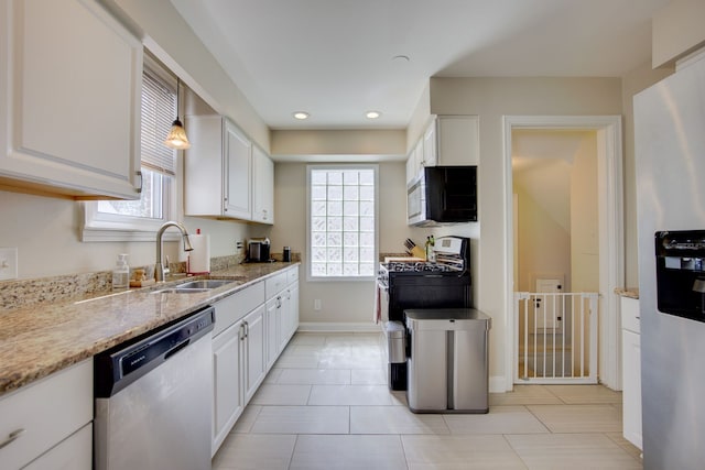 kitchen featuring appliances with stainless steel finishes, a sink, white cabinetry, baseboards, and recessed lighting