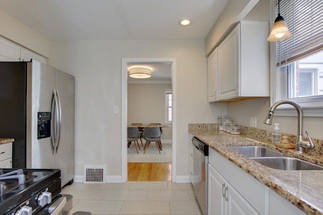kitchen with stainless steel appliances, a sink, white cabinetry, light stone countertops, and recessed lighting