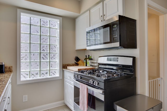 kitchen with stainless steel appliances, white cabinetry, baseboards, and light tile patterned flooring