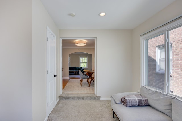 sitting room with arched walkways, light colored carpet, baseboards, and recessed lighting