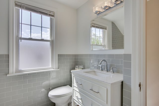 bathroom featuring tile walls, vanity, and toilet