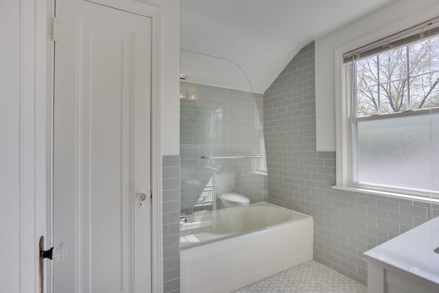 bathroom with tile walls, tile patterned flooring, vaulted ceiling, and plenty of natural light