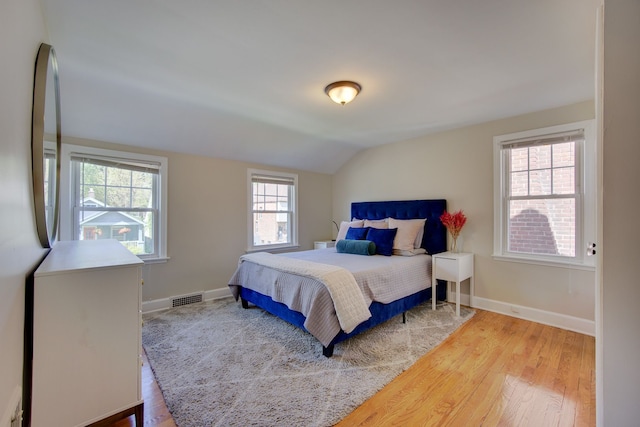 bedroom with vaulted ceiling, wood finished floors, and baseboards