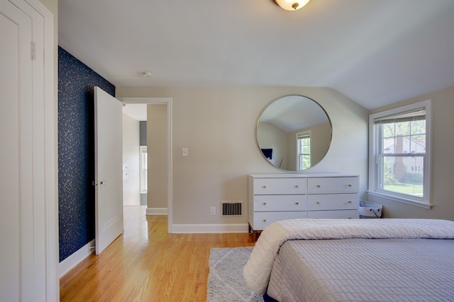 bedroom featuring light wood-style floors, vaulted ceiling, and baseboards