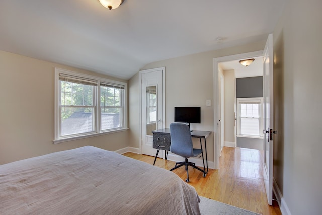 bedroom with vaulted ceiling, light wood-type flooring, baseboards, and a desk