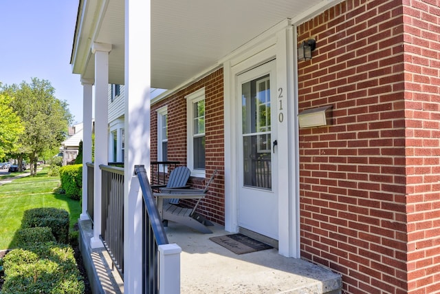doorway to property featuring a porch and brick siding