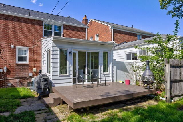 back of house featuring a deck, a chimney, and brick siding