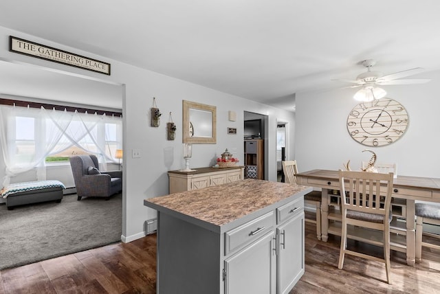 19354 Bueche Rd, New Lothrop, MI 48460 - kitchen featuring dark wood-style flooring, a kitchen island, ceiling fan, light countertops, and baseboards