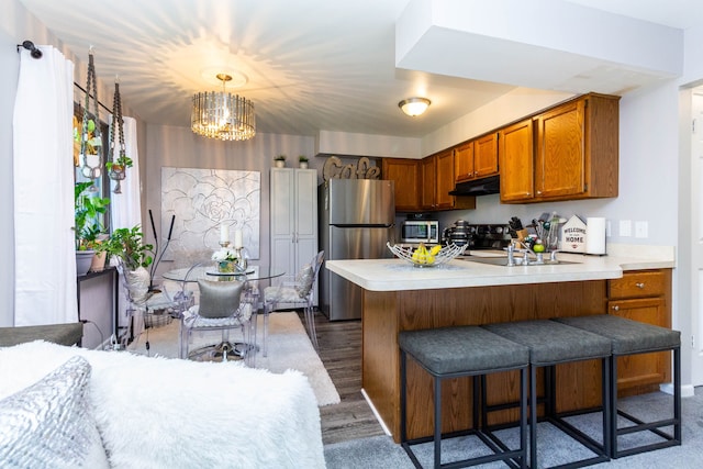 38554 Lanse Creuse St, Harrison Township, MI 48045 - kitchen with appliances with stainless steel finishes, brown cabinets, a chandelier, a peninsula, and light countertops