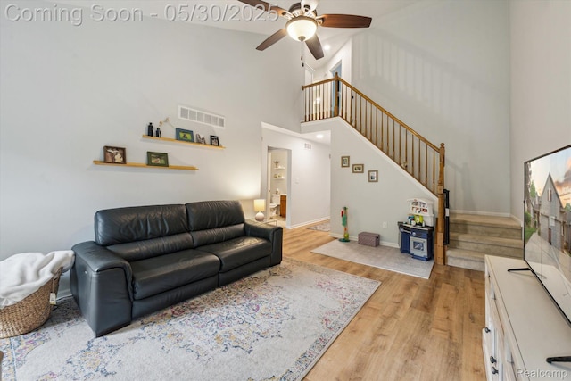 326 Redmaple Ln, Brighton, MI 48116 - living room with stairs, a ceiling fan, light wood-style floors, a towering ceiling, and baseboards