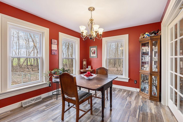 10191 84th St SE, Alto, MI 49302 - dining space featuring a chandelier, wood finished floors, and baseboards