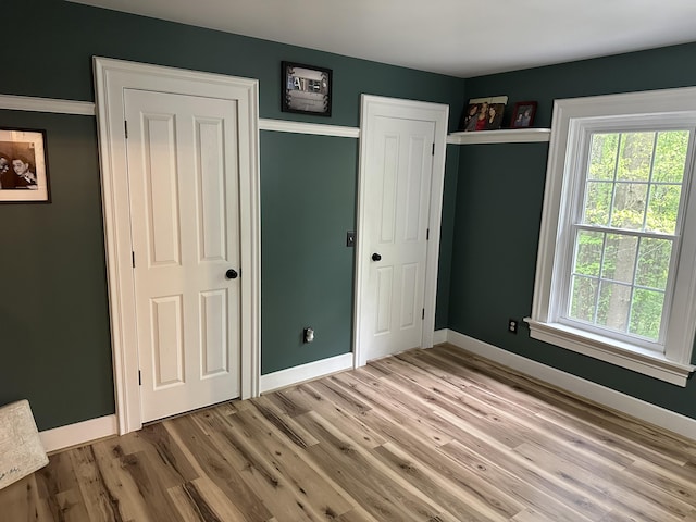 10191 84th St SE, Alto, MI 49302 - unfurnished bedroom featuring baseboards, wood finished floors, and multiple windows
