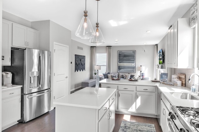 27144 Silo Dr, Saline, MI 48176 - kitchen with stainless steel appliances, a sink, a peninsula, dark wood-style flooring, and light countertops