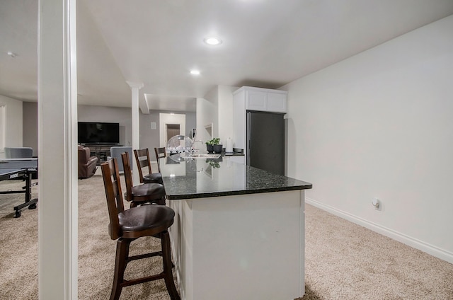 4181 Pavilion Ct, Fenton, MI 48430 - kitchen featuring carpet, freestanding refrigerator, baseboards, white cabinetry, and a breakfast bar area