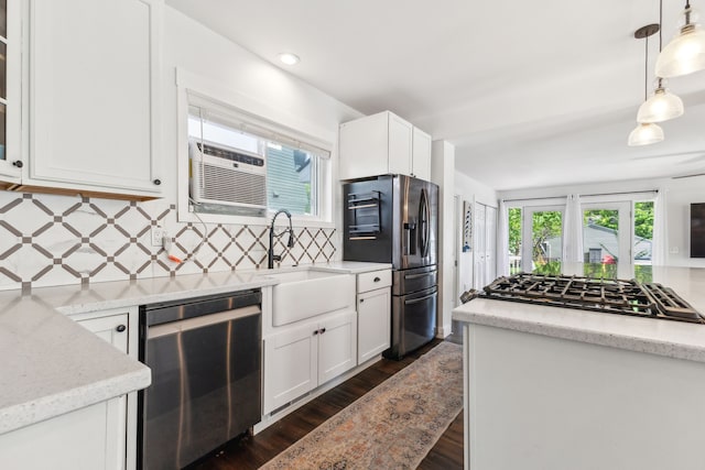 kitchen featuring appliances with stainless steel finishes, a sink, tasteful backsplash, dark wood-type flooring, and white cabinetry