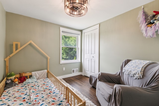 bedroom featuring wood finished floors, a closet, baseboards, and a chandelier