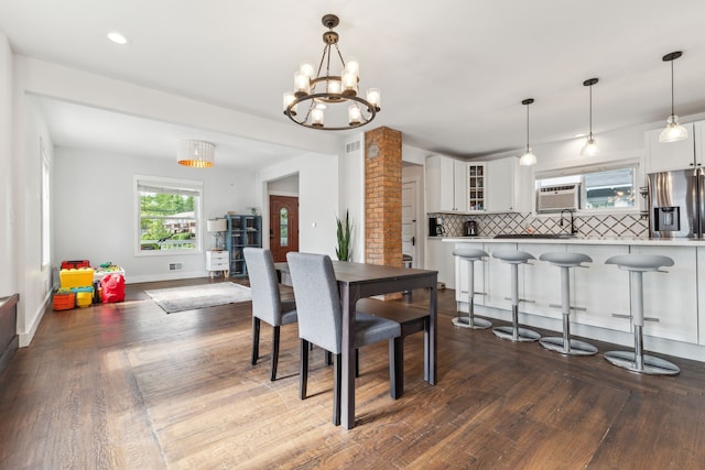 dining area with dark wood-style flooring, a chandelier, and baseboards