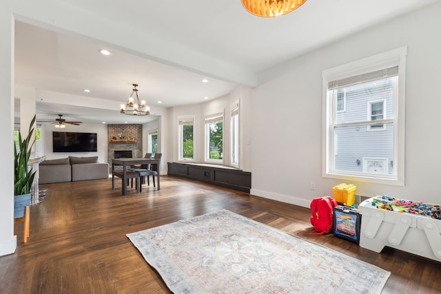 living room with a brick fireplace, baseboards, a chandelier, recessed lighting, and dark wood-type flooring