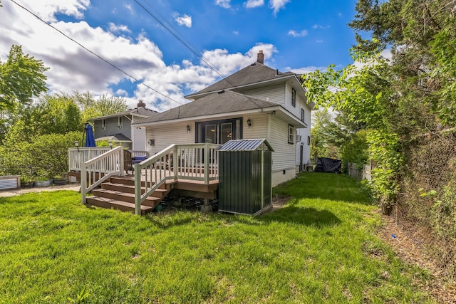 back of house with a deck, a yard, a chimney, and roof with shingles