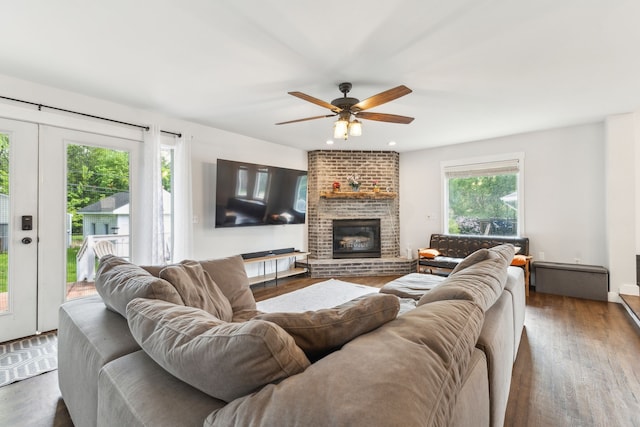living room with wood finished floors, a brick fireplace, and ceiling fan