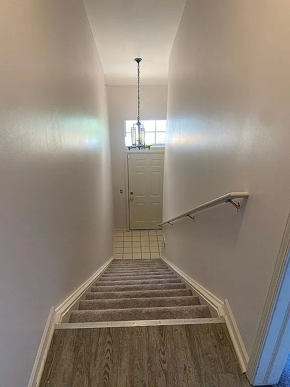 18203 Adri Cir, Walled Lake, MI 48390 - staircase with wood finished floors, baseboards, and a chandelier