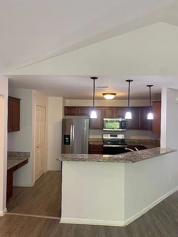 18203 Adri Cir, Walled Lake, MI 48390 - kitchen with appliances with stainless steel finishes, dark wood-type flooring, dark stone countertops, and dark brown cabinets