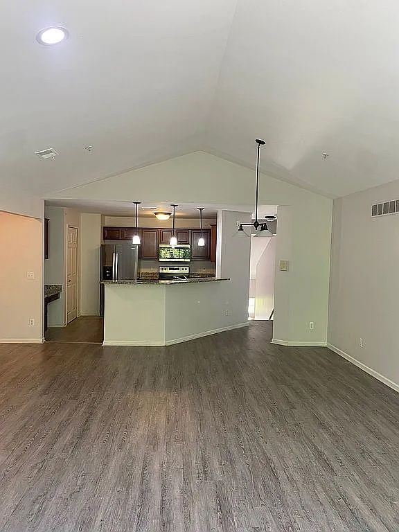 18203 Adri Cir, Walled Lake, MI 48390 - unfurnished living room featuring dark wood finished floors, vaulted ceiling, and baseboards