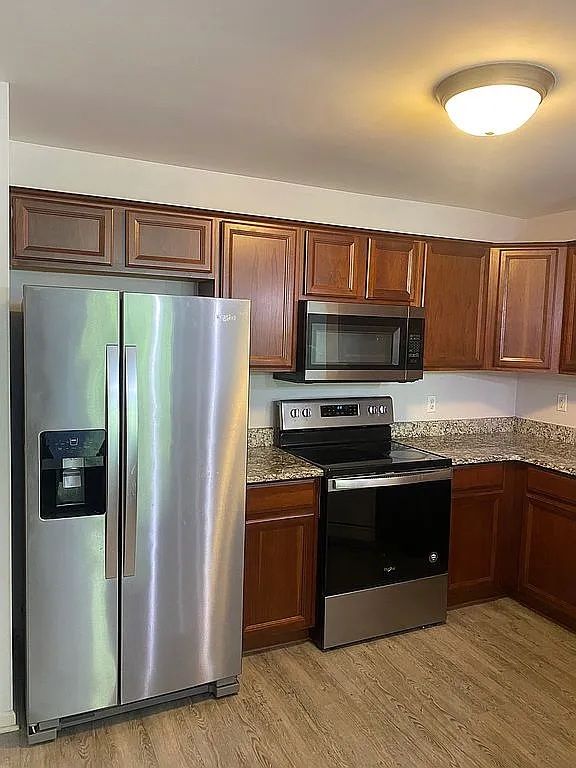 18203 Adri Cir, Walled Lake, MI 48390 - kitchen with appliances with stainless steel finishes, light wood finished floors, and dark stone countertops
