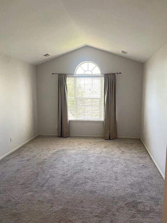 18203 Adri Cir, Walled Lake, MI 48390 - carpeted spare room featuring lofted ceiling and baseboards