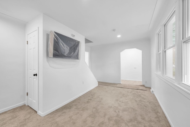 below grade area featuring carpet floors, arched walkways, baseboards, and recessed lighting