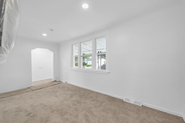carpeted spare room with arched walkways, baseboards, and recessed lighting