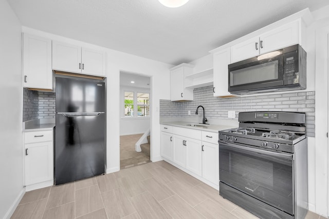 kitchen with black appliances, a sink, light countertops, and decorative backsplash