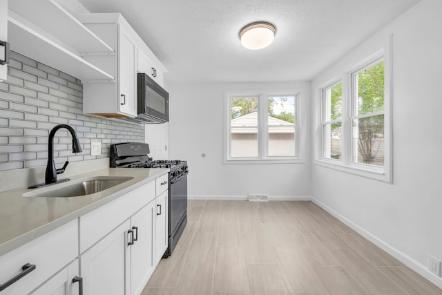 kitchen with black appliances, a sink, light countertops, baseboards, and open shelves