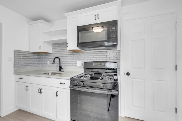 kitchen featuring black appliances, a sink, tasteful backsplash, light countertops, and white cabinetry