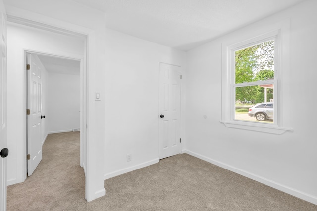 unfurnished bedroom with light carpet and baseboards