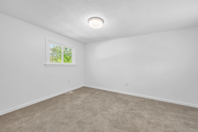 empty room featuring carpet floors, baseboards, and a textured ceiling