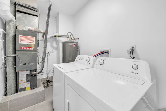 clothes washing area with washing machine and clothes dryer, water heater, and wood finished floors