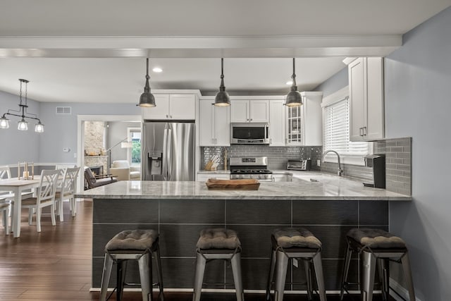kitchen with appliances with stainless steel finishes, light stone counters, white cabinets, a peninsula, and recessed lighting