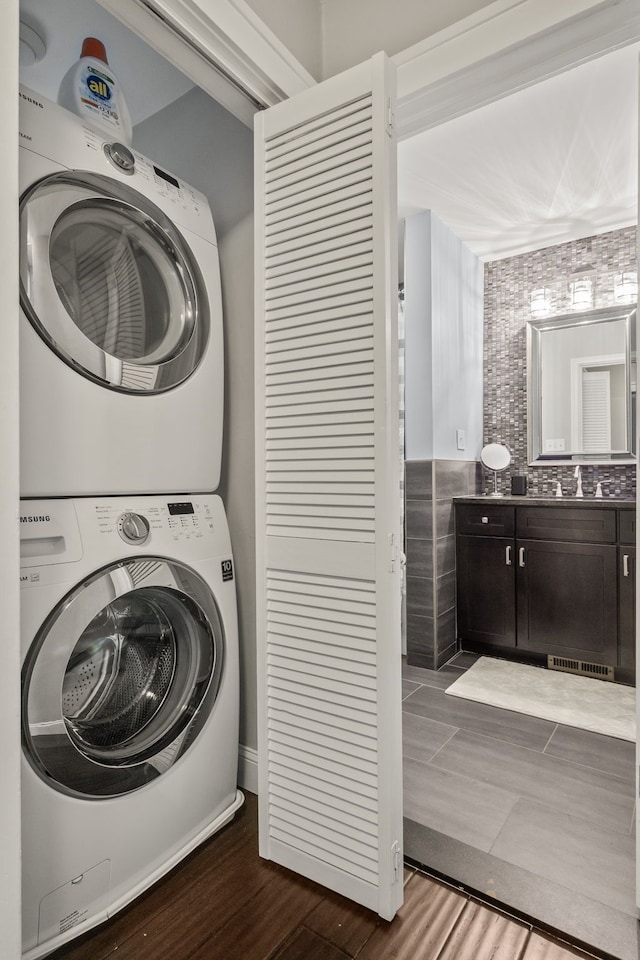 washroom featuring stacked washer / drying machine and dark wood finished floors