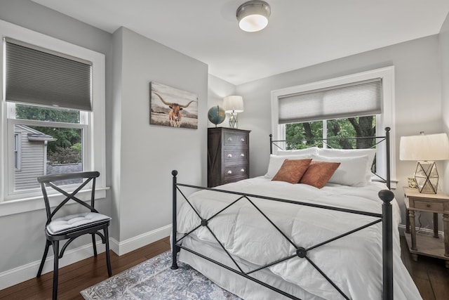 bedroom with multiple windows, wood finished floors, and baseboards