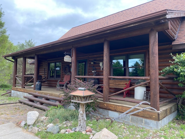 5114 N Oak Rd, Davison, MI 48423 - view of exterior entry with covered porch, roof with shingles, and log siding