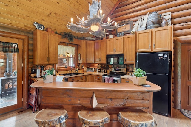 5114 N Oak Rd, Davison, MI 48423 - kitchen with black appliances, a sink, rustic walls, light wood finished floors, and a chandelier