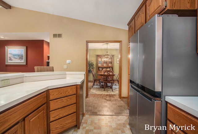 607 Crestview St, Holland, MI 49423 - kitchen featuring freestanding refrigerator, lofted ceiling, brown cabinets, light countertops, and a chandelier