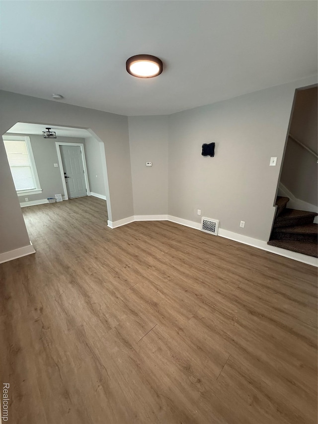 816 12th St, Port Huron, MI 48060 - unfurnished living room with arched walkways, wood finished floors, stairs, and baseboards